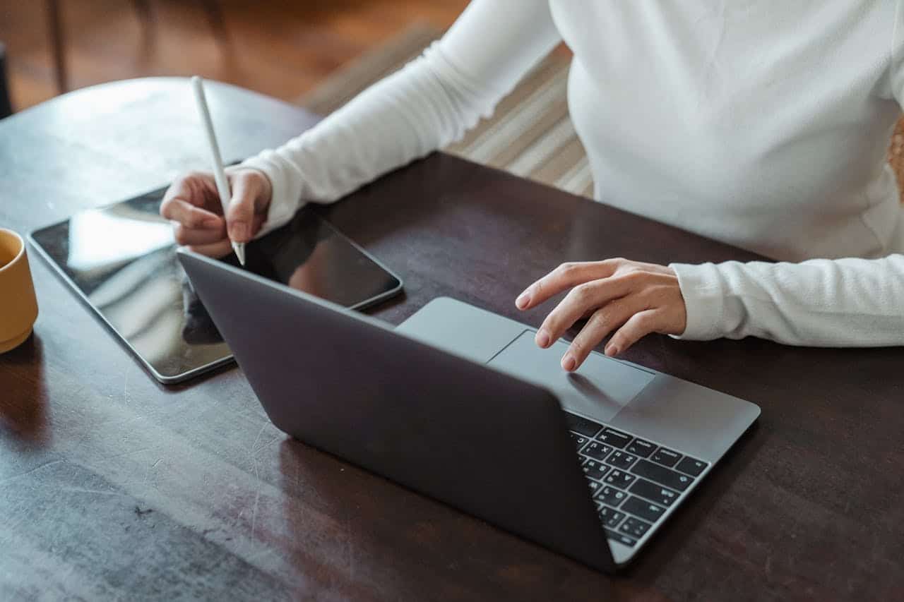 A landscaping business owner planning out their work schedule on a laptop and tablet.